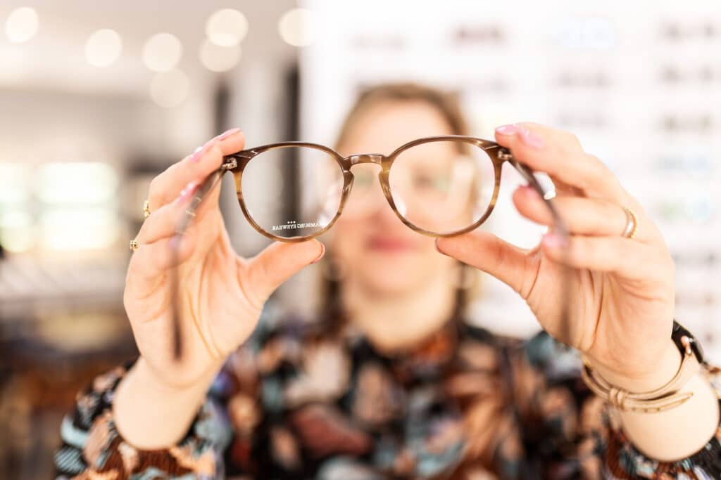 Frau hält Brille in die Kamera